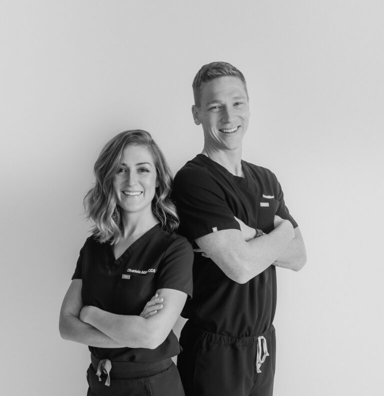 Black and white photo of Drs. Danielle and Dan Miller of Wildhorse Dental, standing together in scrubs