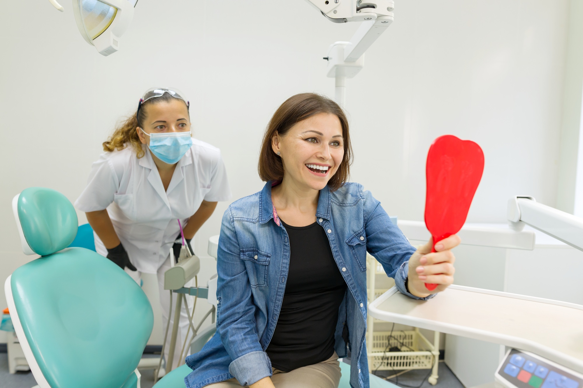 Happy cosmetic dentistry patient seeing smile results in mirror after treatment—example of visual content used in social media marketing by Clear to Launch Dental Marketing.