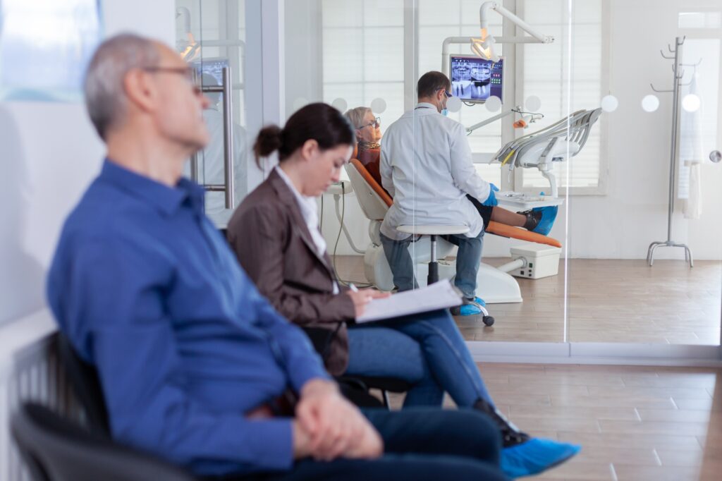 Patients in a dental office waiting room while a dentist treats a patient—illustrating how effective search marketing from Clear to Launch Dental Marketing brings in more new patients.
