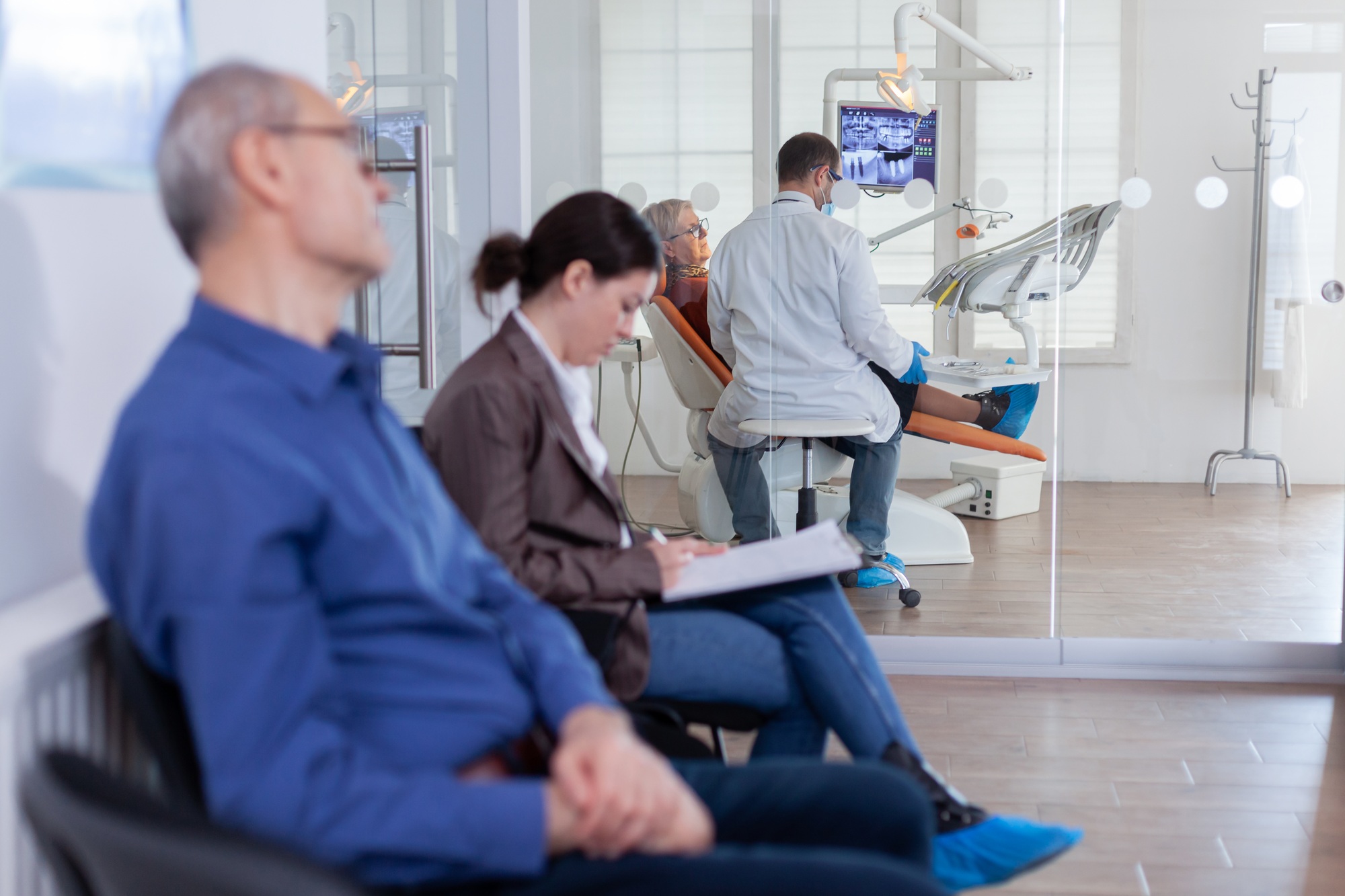 Patients in a dental office waiting room while a dentist treats a patient—illustrating how effective search marketing from Clear to Launch Dental Marketing brings in more new patients.
