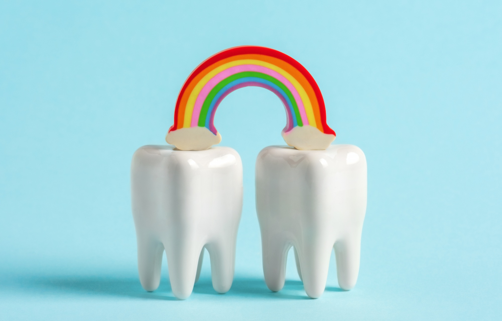 Two connected teeth with a rainbow representing local dental partnerships and community marketing