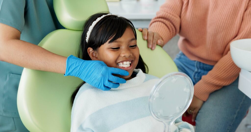 Smiling child at a pediatric dental visit with parent and dentist, representing family-focused dental SEO strategies