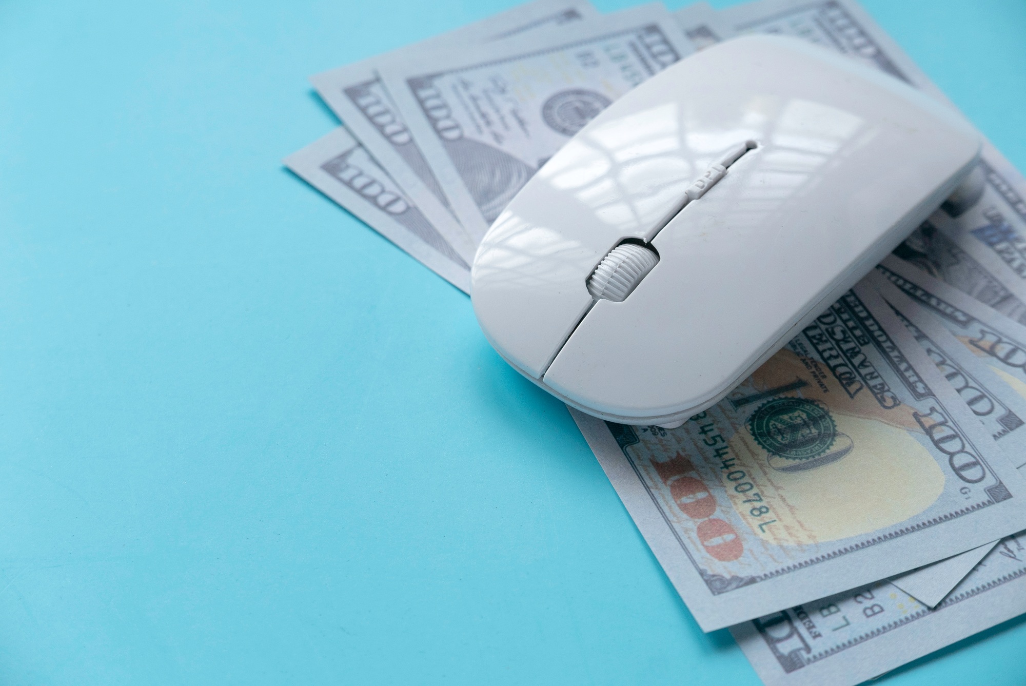 Computer mouse on top of hundred-dollar bills symbolizing pay-per-click (PPC) advertising costs for Healthcare marketing campaigns