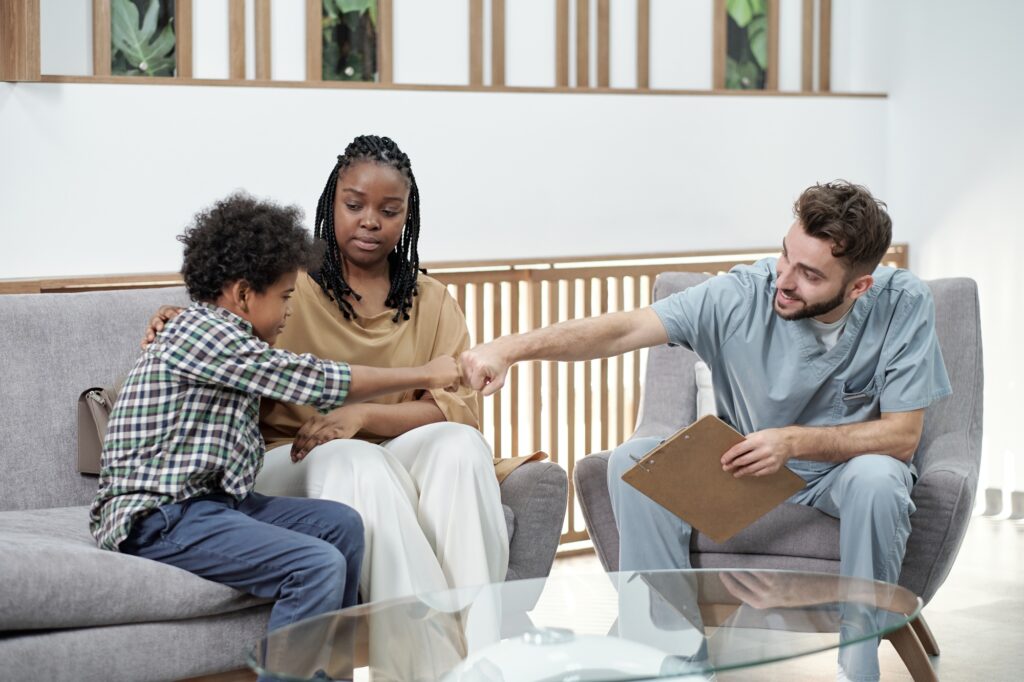 Dentist greeting young patient and parent in office, representing how Clear to Launch Healthcare Marketing uses Google Ads to attract families to dental practices